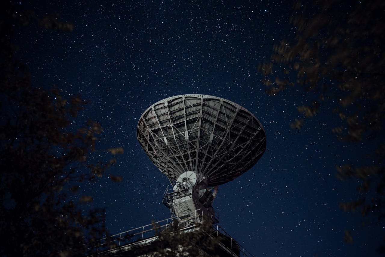 A large radio telescope beneath a starry night sky capturing celestial signals.